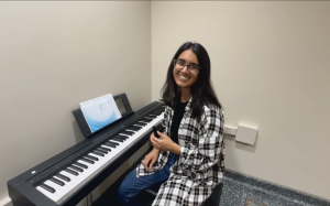Khadijah Dhoondia sits at a piano in the prayer and reflection space in Rennebohm Hall School of Pharmacy.